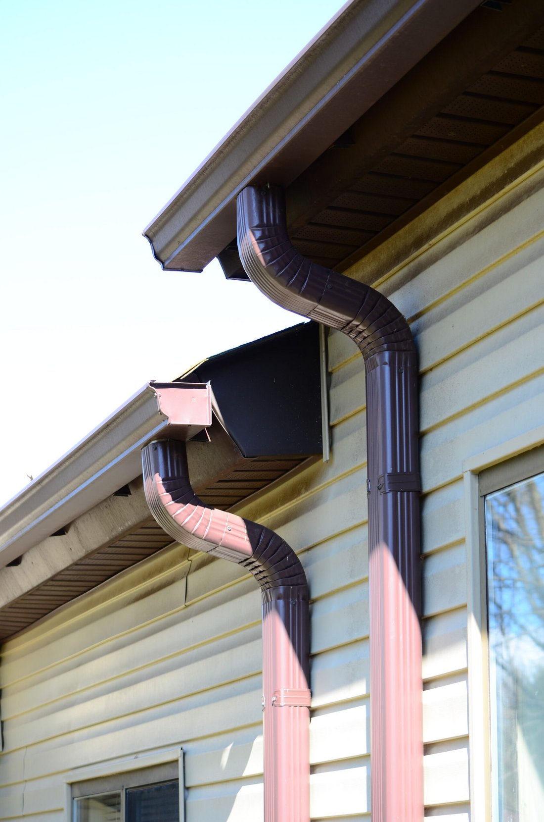 New gutters and downspouts installed on the side of a house
